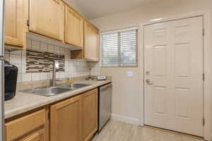 Kitchen featuring tasteful backsplash and new faucet. Door leads to smalll, private patio