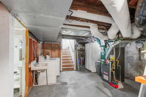 Basement featuring washer and clothes dryer and heating unit