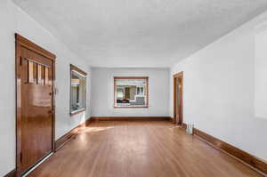 Empty room with light hardwood / wood-style floors and a textured ceiling