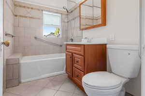 Full bathroom featuring tiled shower / bath, vanity, toilet, and tile patterned floors