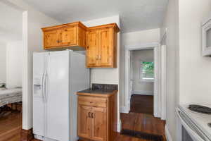 Kitchen with a textured ceiling, white appliances, and dark hardwood / wood-style flooring