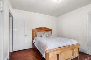 Bedroom with a textured ceiling and dark hardwood / wood-style floors