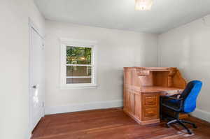 Home office featuring dark wood-type flooring and a textured ceiling