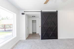 Carpeted empty room with ceiling fan and a barn door