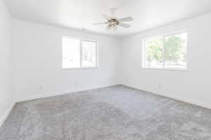 Carpeted empty room featuring ceiling fan and plenty of natural light