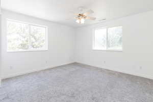 Carpeted spare room with a healthy amount of sunlight and ceiling fan