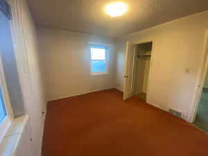 Unfurnished bedroom featuring carpet, a textured ceiling, and a closet