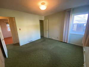 Carpeted spare room featuring a textured ceiling