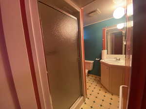 Bathroom with a shower with door, toilet, crown molding, and vanity