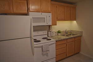 Kitchen featuring white appliances, light tile patterned floors, and sink