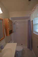 Bathroom with vanity, tile patterned floors, curtained shower, and toilet