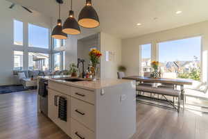 Kitchen featuring white cabinetry, a wealth of natural light, a kitchen island with sink, and sink