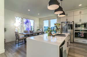 The vast open kitchen overlooks a charming park visible through the picture windows. The waterfall countertop, wall oven/ microwave, built-in range, layered lighting and ample cupboard space to the ceiling will make this kitchen a favorite gathering space