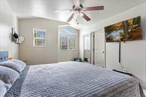 Bedroom featuring ceiling fan, a textured ceiling, and lofted ceiling