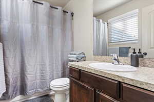 Bathroom with vanity, a shower with curtain, and toilet