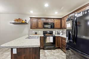 Kitchen featuring sink, black appliances, brown cabinets and kitchen peninsula