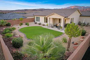 Back of house with a lawn, a mountain view, and a patio area