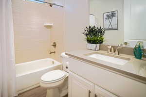 Steel tub with tile surround. Single vanity with quartz counters and upgraded lighting.