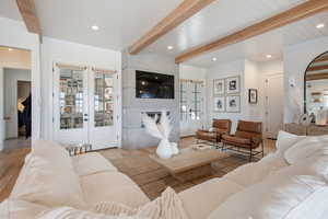 Living room with light hardwood / wood-style flooring, french doors, beamed ceiling, and a fireplace