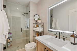 Bathroom with toilet, tile patterned floors, walk in shower, tile walls, and vanity