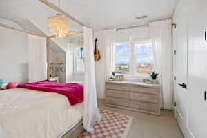 Bedroom with light colored carpet and an inviting chandelier