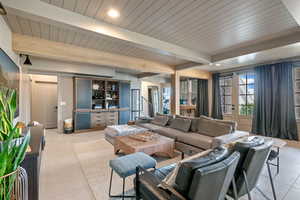 Living room with beam ceiling, light tile patterned flooring, and wood ceiling