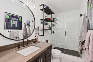 Bathroom with toilet, walk in shower, vanity, and tile patterned flooring