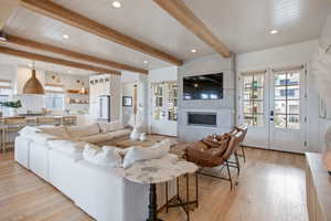 Living room with beam ceiling, a fireplace, light hardwood / wood-style floors, french doors, and sink