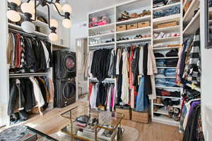 Spacious closet featuring stacked washer / dryer and light hardwood / wood-style flooring