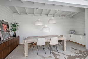 Dining space with vaulted ceiling with beams and wooden walls