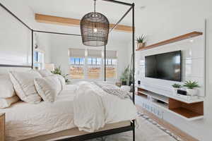 Bedroom featuring an inviting chandelier, beam ceiling, and wood-type flooring