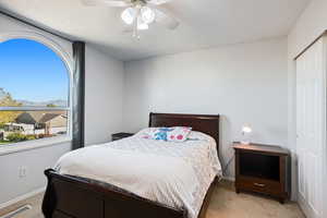 Bedroom featuring light colored carpet, a closet, and ceiling fan