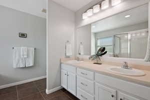 Bathroom featuring vanity, tile patterned floors, and a shower with door