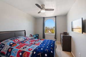 Bedroom with a textured ceiling, light colored carpet, and ceiling fan