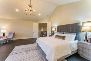 Bedroom with vaulted ceiling, a notable chandelier, and dark hardwood / wood-style flooring