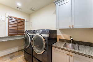 Laundry area with sink, washer and clothes dryer, and cabinets