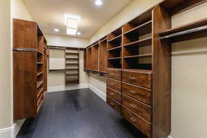 Walk in closet with dark wood-type flooring