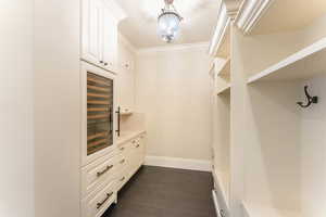 Walk in closet with dark hardwood / wood-style flooring and beverage cooler