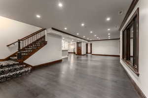 Unfurnished living room featuring ornamental molding and dark hardwood / wood-style floors