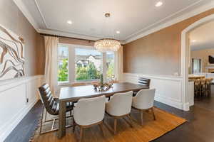 Dining space with ornamental molding, an inviting chandelier, and dark hardwood / wood-style floors