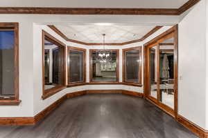 Interior space with ornamental molding, dark hardwood / wood-style floors, and an inviting chandelier