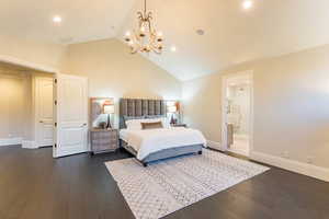 Bedroom with dark wood-type flooring, connected bathroom, high vaulted ceiling, and a chandelier