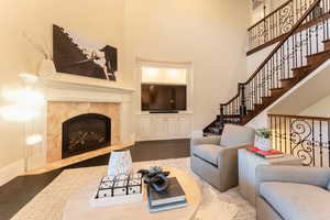 Living room featuring a premium fireplace, hardwood / wood-style floors, and a towering ceiling