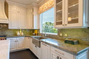 Kitchen featuring dark hardwood / wood-style flooring, sink, white cabinets, and tasteful backsplash