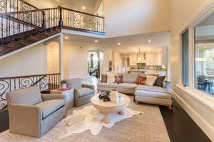 Living room featuring hardwood / wood-style flooring, a healthy amount of sunlight, and a towering ceiling