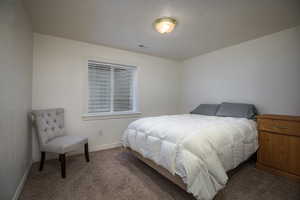 Bedroom with dark colored carpet and a textured ceiling