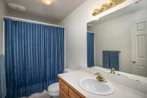 Bathroom with vanity, toilet, and a textured ceiling