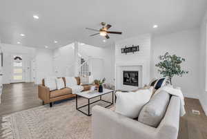 Living room featuring a large fireplace, hardwood / wood-style flooring, and ceiling fan