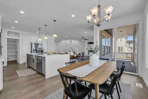 Dining room with sink, light wood-type flooring, and ceiling fan with notable chandelier