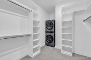 Spacious closet featuring light carpet and stacked washing maching and dryer